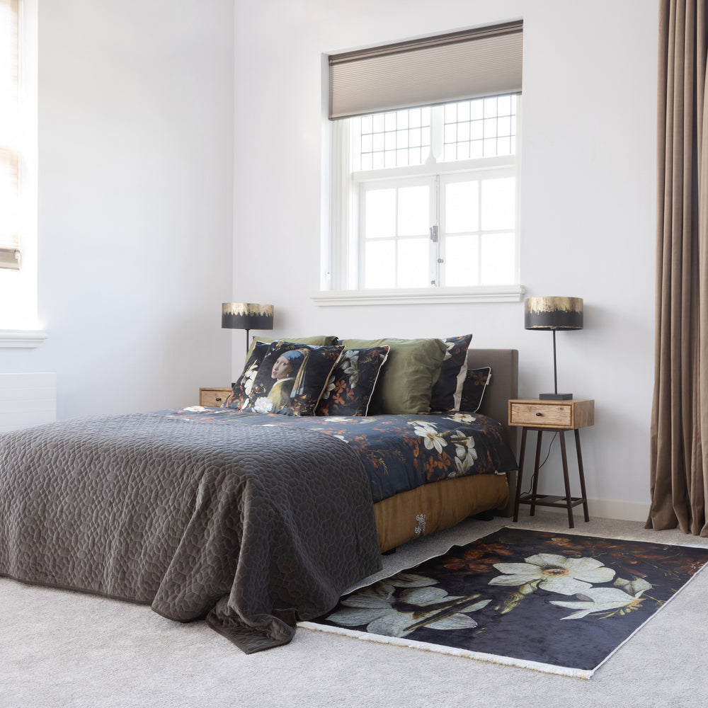 Sfeervolle slaapkamerhoek met de Blackout lamp, Skybox sidetable van mangohout, een opgedekt bed en een kleurrijk vloerkleed.
