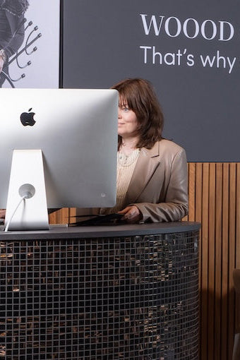 Medewerker bij de informatie- en kassabalie in het experience center, bezig met het opzoeken van gegevens op een scherm