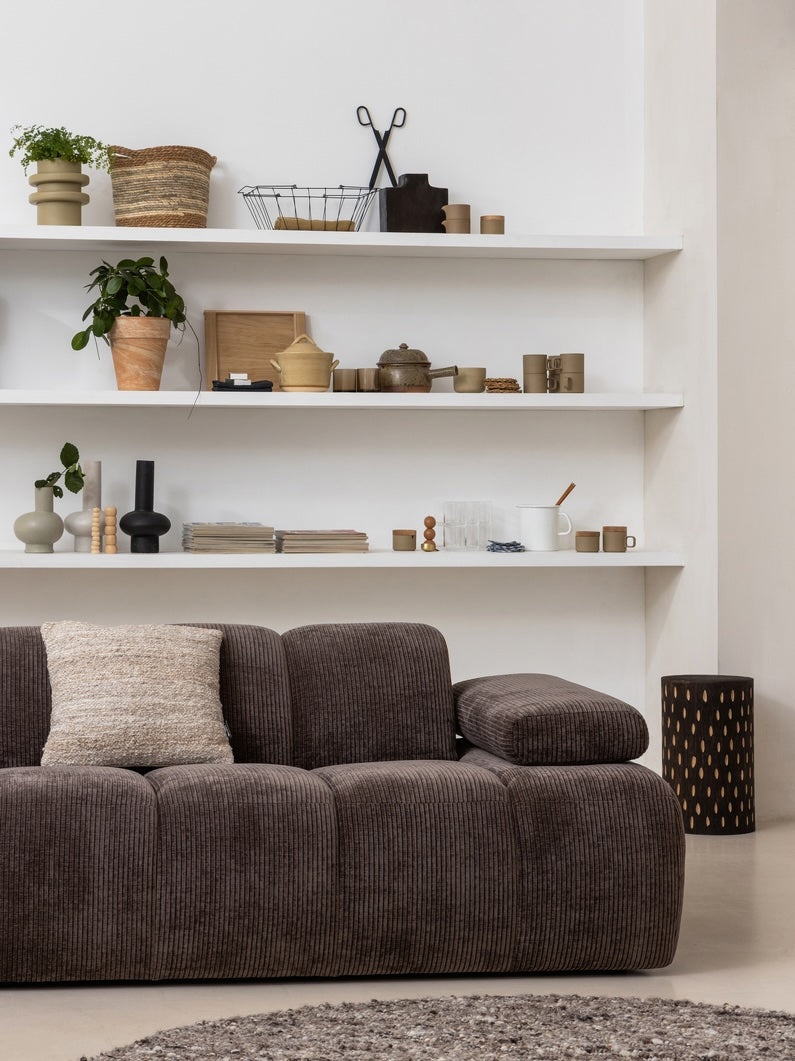 Stijlvolle zithoek met Mojo 1,5-zits, geplaatst voor een decoratieve muur met ingebouwde planken vol woonaccessoires.